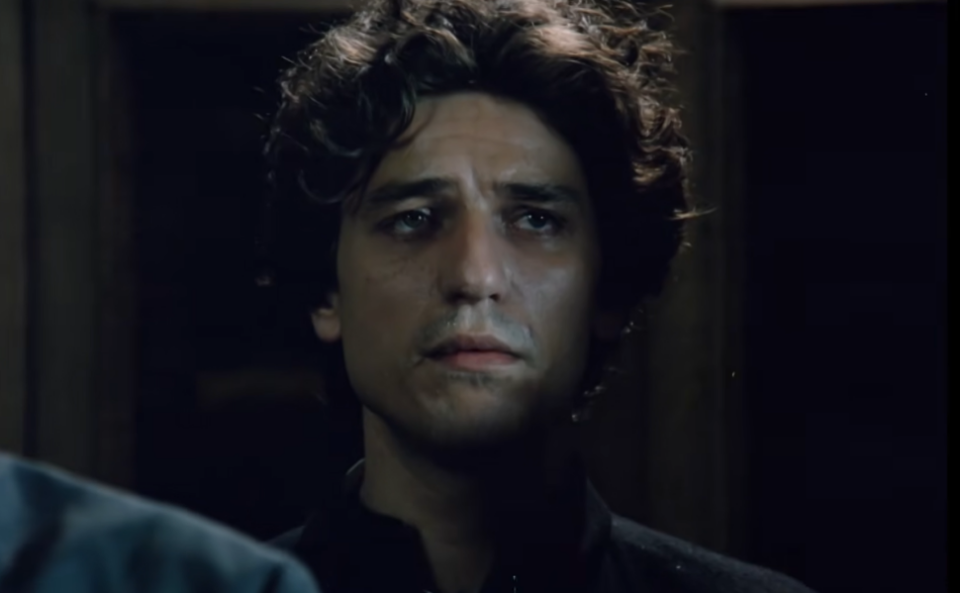 Кадар од југословенскиот хорор-филм „Свето место“ (1990) во режија на Ѓорѓе Кадијевиќ, со вознемирен машки лик во затемнета просторија.